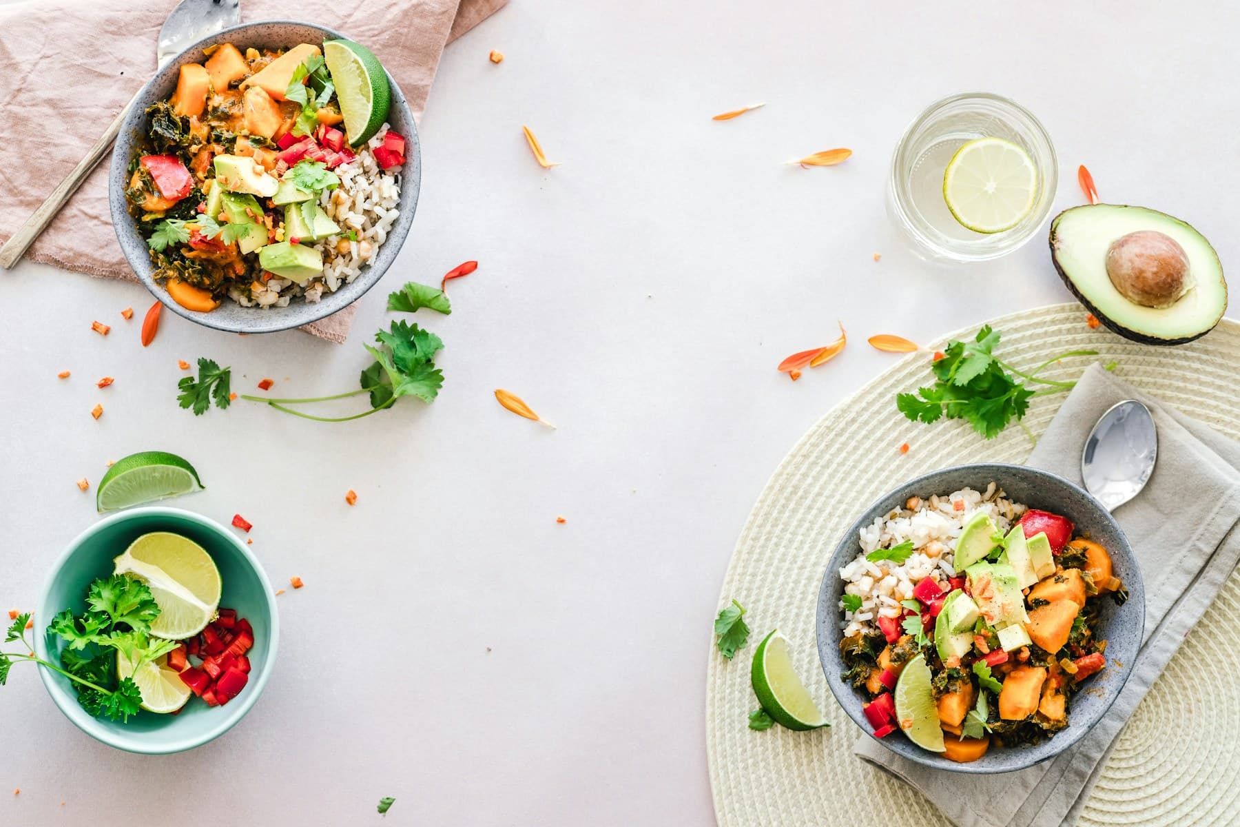 Bright bowls of rice, avocado, sweet potato, and lime on a kitchen table